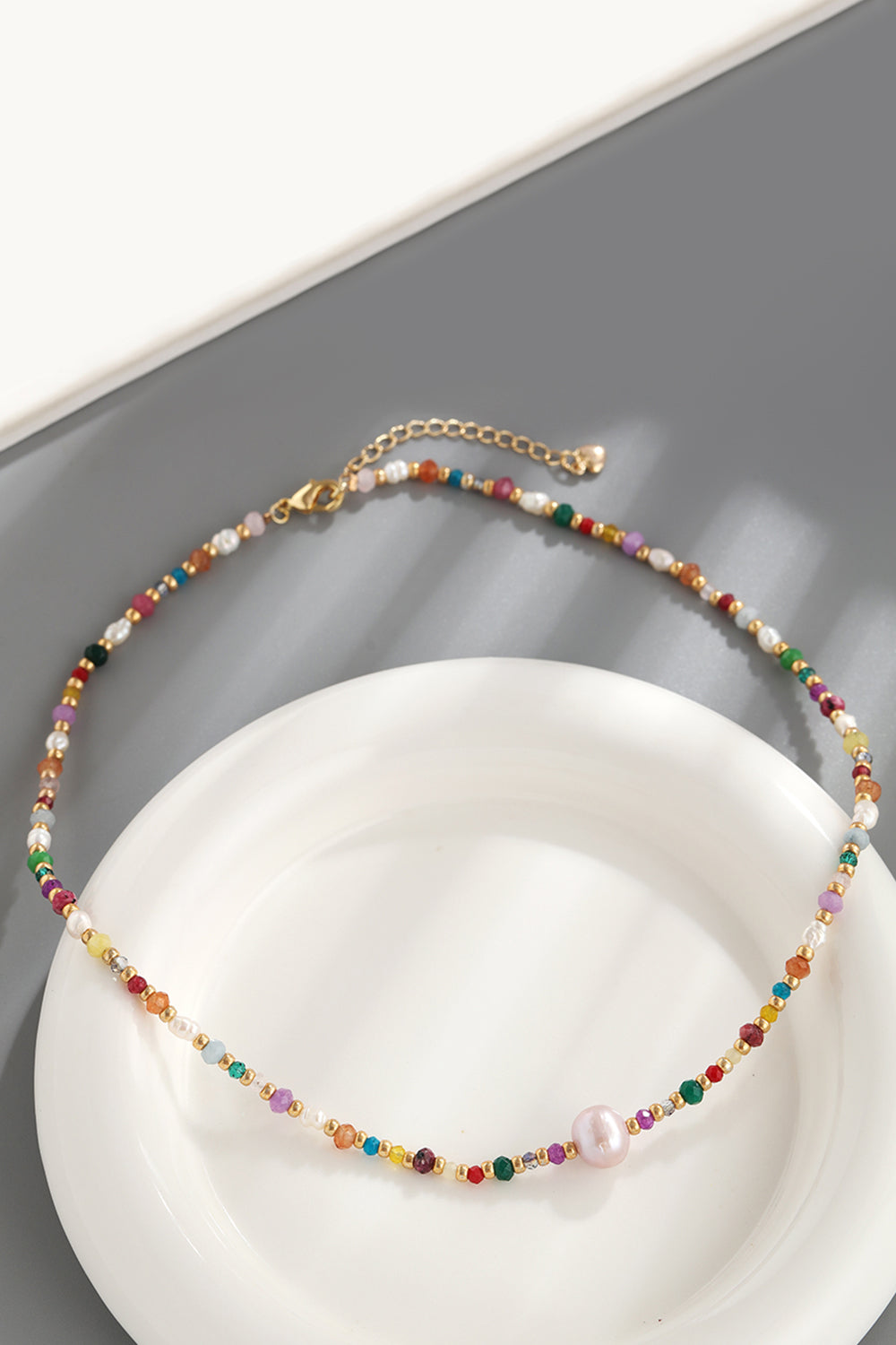 Alt Tag: multicolored bead necklace with freshwater pearls featuring crystal beads and gold clasp on white plate