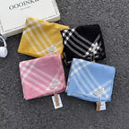 classic plaid scarf set in yellow, black, pink and blue polyester fiber, folded and displayed on textured surface