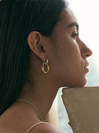 18K gold-plated asymmetrical earrings worn by a model, showcasing contrast design with stainless steel, side profile view