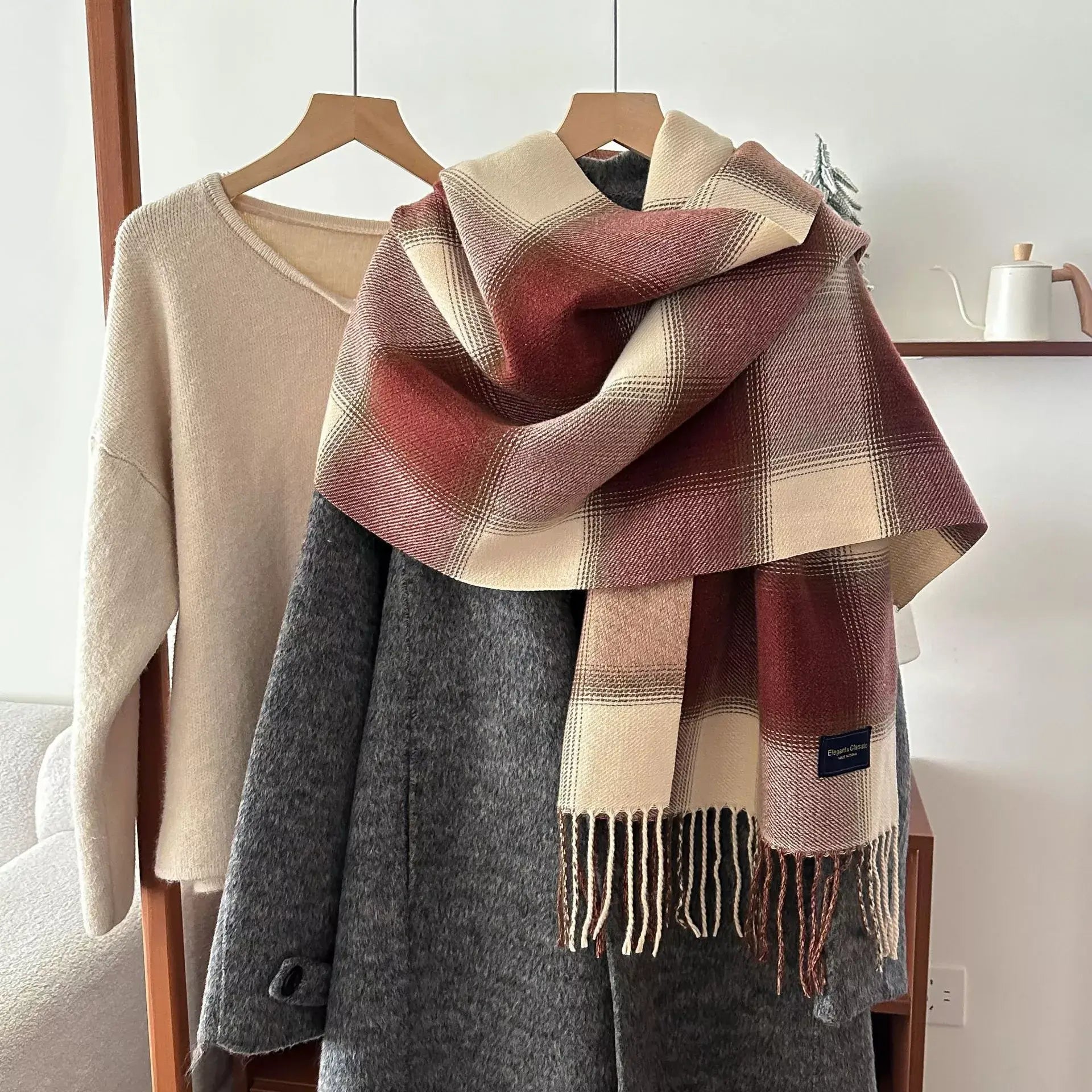 plaid fringe scarf in burgundy and beige draped over gray coat on hanger, soft polyester imported winter accessory