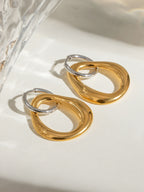 18K gold-plated asymmetrical earrings in stainless steel with contrasting design on a light surface
