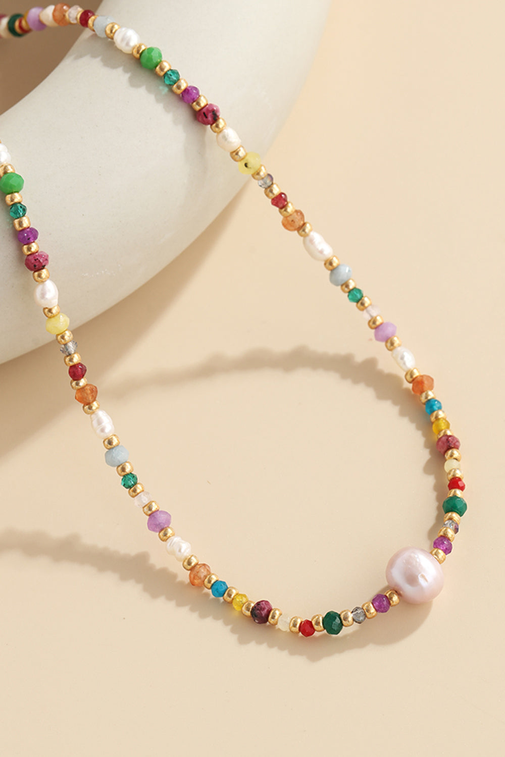Alt Tag: multicolored bead necklace with freshwater pearls featuring crystal beads and pearl pendant on beige background