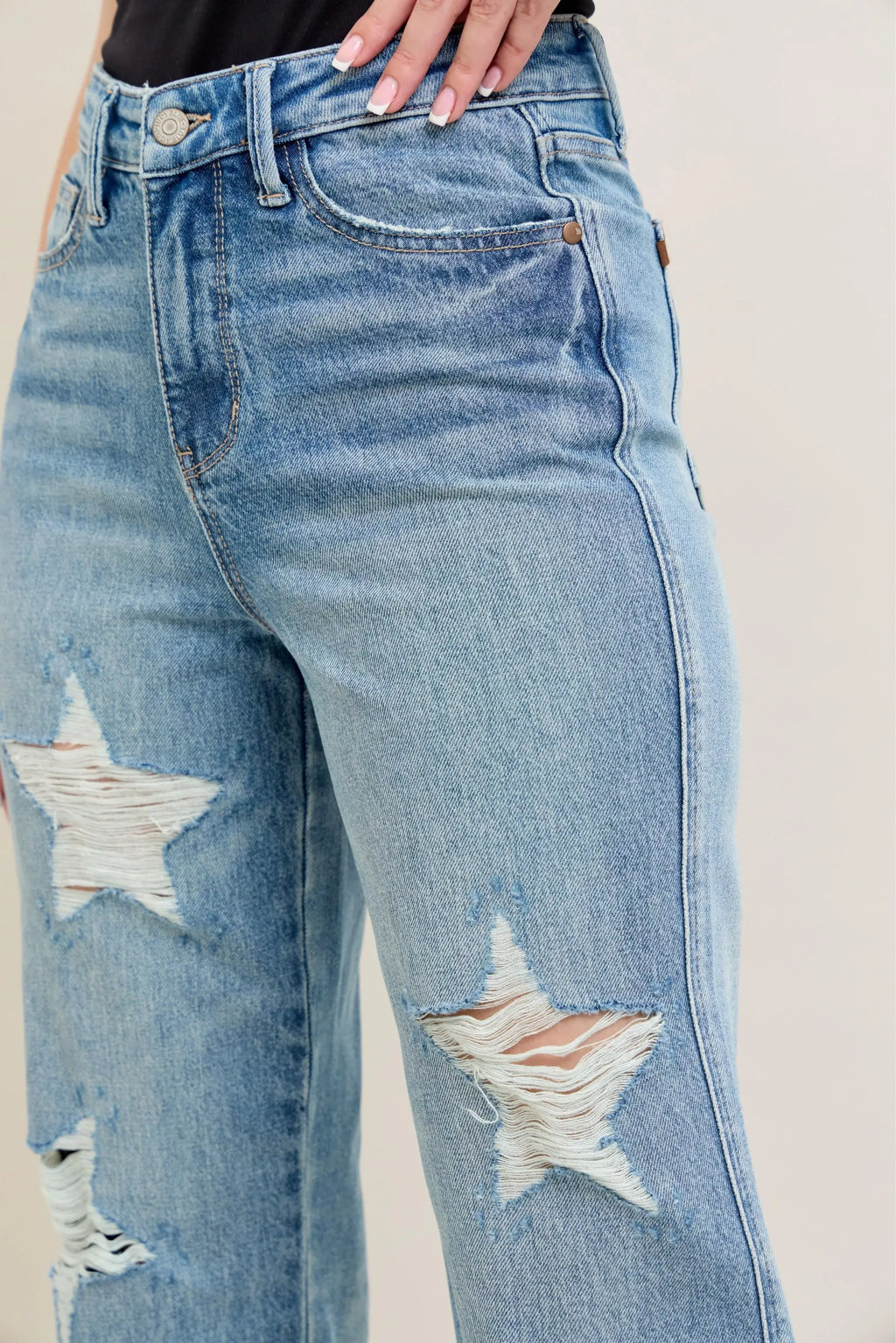 Close-up of plus size 90s high waist jeans with star-shaped destroy details and a trendy retro design.